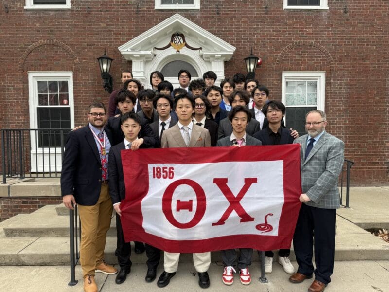 Group photo with fraternity members holding flag.
