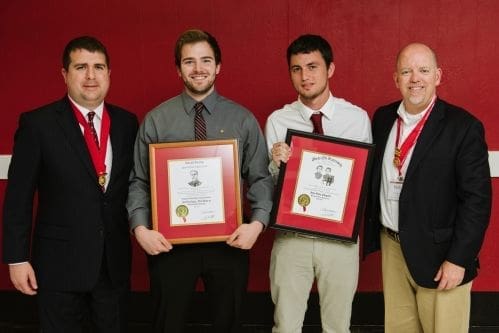 Four men holding awards at a recognition ceremony.