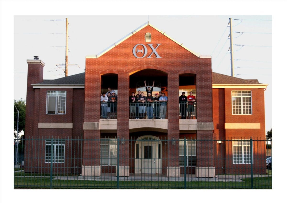 Group of students at fraternity house balcony.