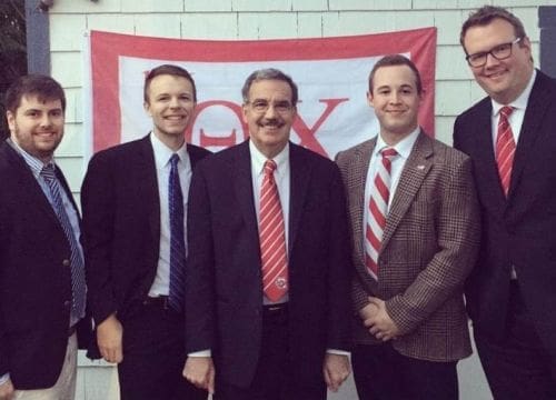 Group of men posing in front of a banner.