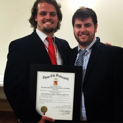 Two men celebrating a fraternity achievement with certificate.
