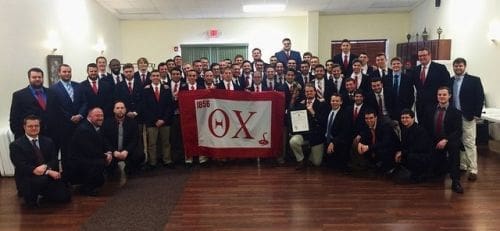 Group photo of fraternity members with banner.