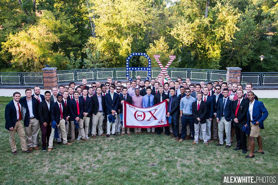 Group photo of fraternity members with banner.