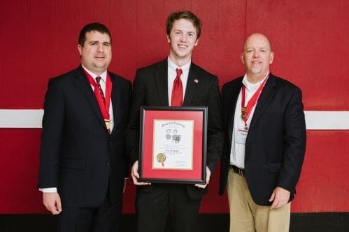 Three men holding an award certificate proudly.