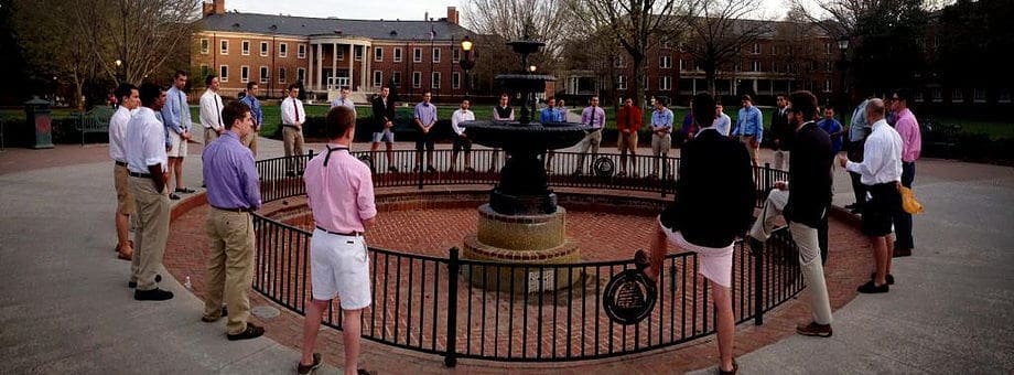 Group of men gathered around a fountain outdoors.