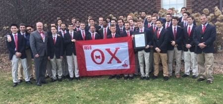 Group photo of Theta Chi fraternity members with flag.