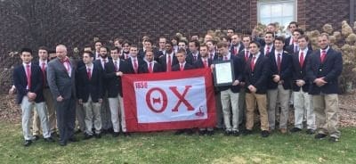 Group of fraternity members posing with flag.