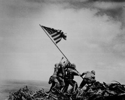 Soldiers raising the American flag on a battlefield.