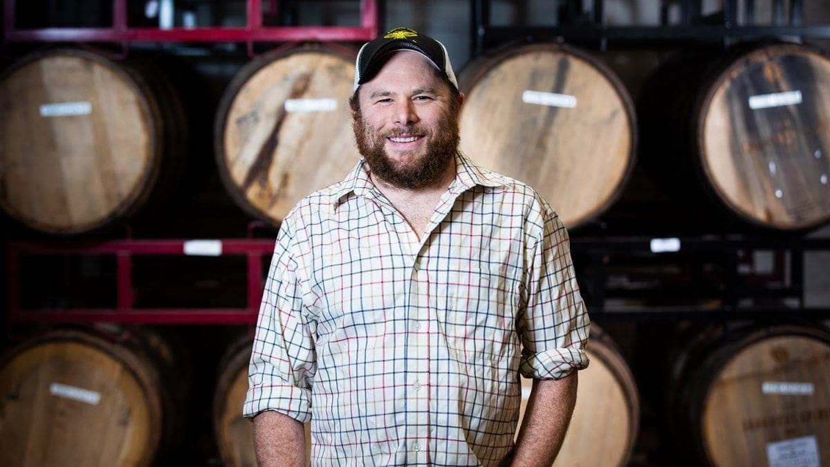 Smiling man in front of wooden barrels.