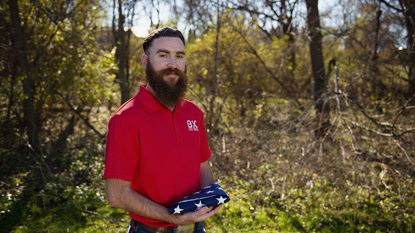 Man holding folded American flag outdoors.
