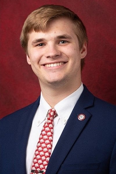 Jared Pinkerton - Arkansas Smiling man in suit with red tie and pin.
