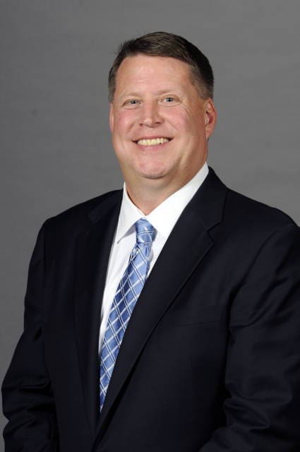 Smiling man in a suit with a blue tie.