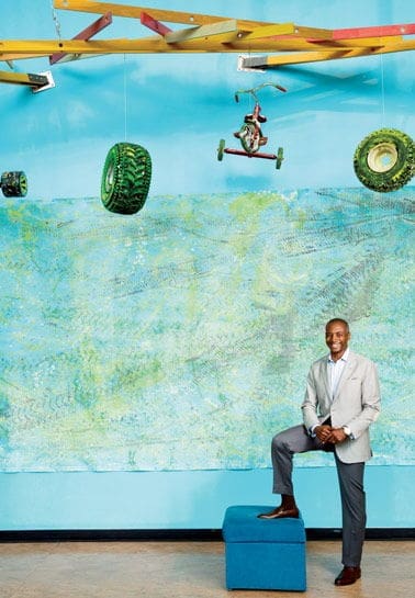 Jeff Perry Man in suit poses against colorful abstract backdrop.