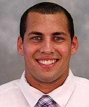 Smiling man in formal attire with purple tie.