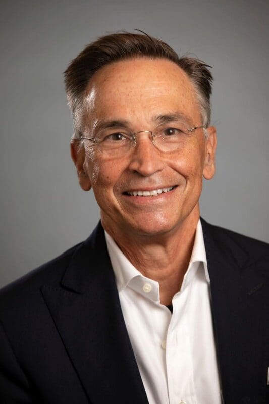 Smiling man in glasses wearing a suit.