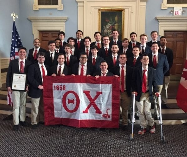 Group of fraternity members with banner and certificate.