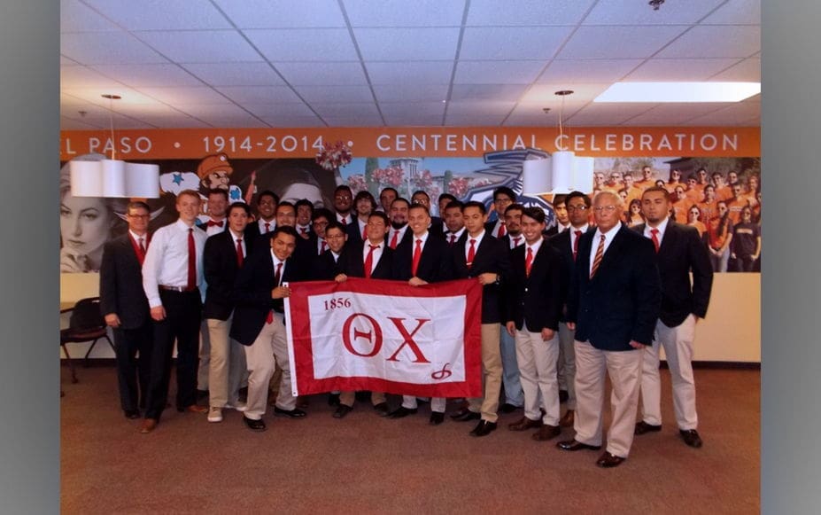 Group photo of fraternity members holding banner.