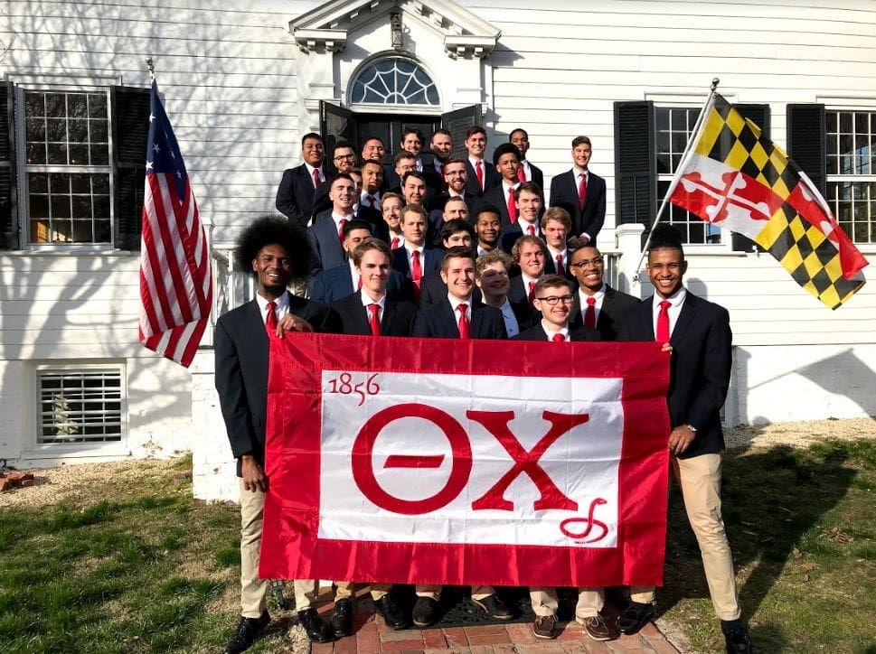 Group photo of fraternity members with flag.