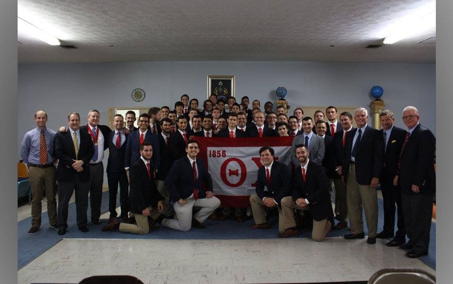 Group photo of fraternity members with flag.