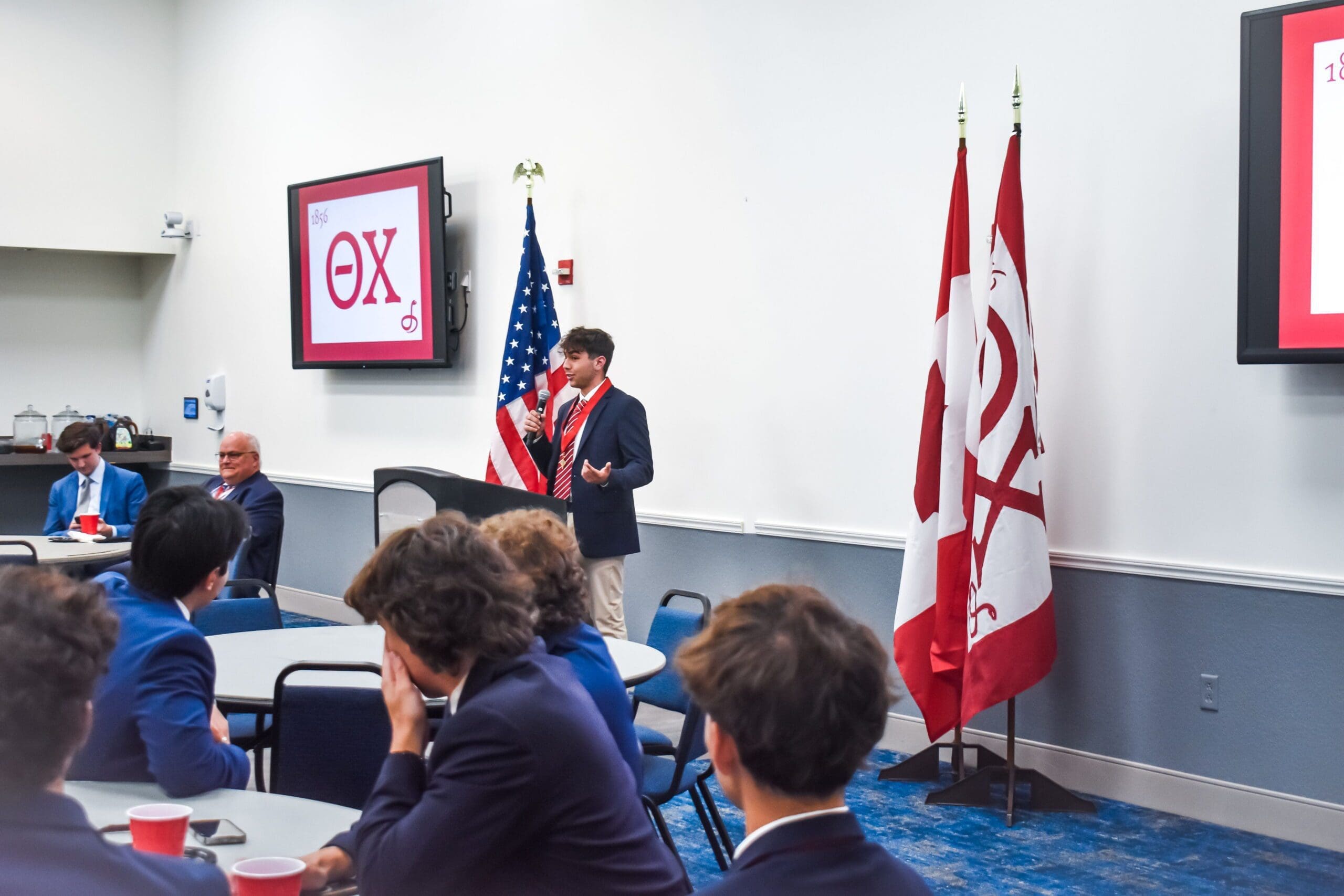 Student presenting at conference with flags in background.