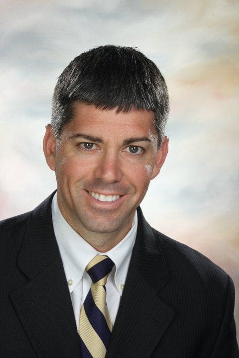 Professional headshot of a man in a suit.