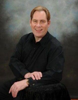 Smiling man in black shirt posing for portrait.