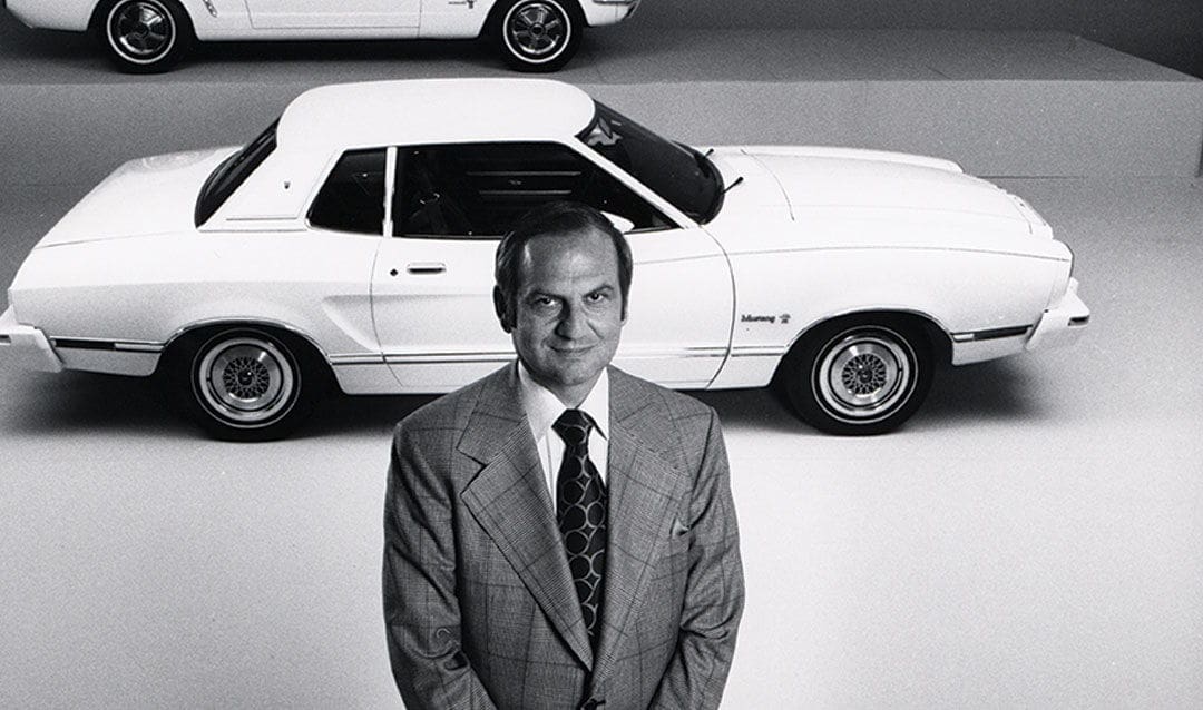 Lee Iacocca Man in suit with classic white convertible car.