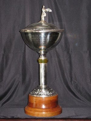 Silver trophy with ornate detailing on black background.