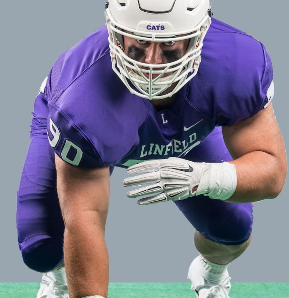Football player in Linfield uniform preparing to tackle.