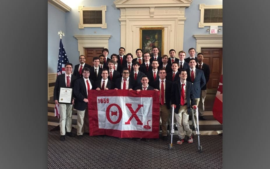 Group of fraternity members with flag and certificates.