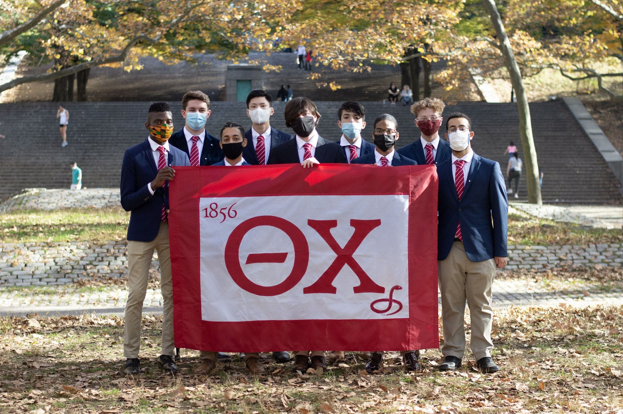 Long Island-Brooklyn Group of students holding fraternity flag outdoors.
