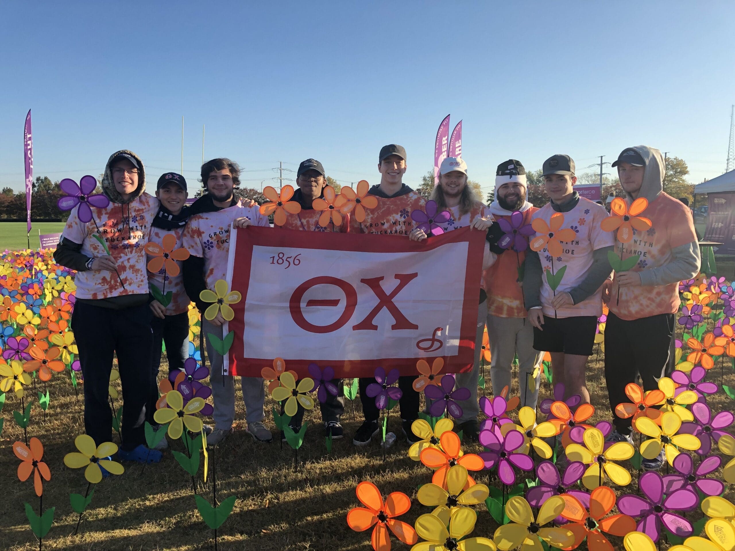 Team posing with flowers and a banner.