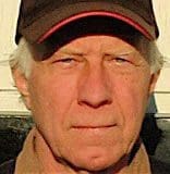 Older man wearing a cap, serious expression.