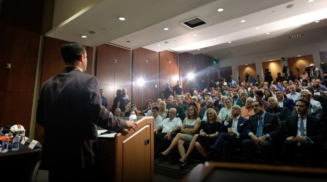 Manny Diaz Speaker addressing large audience in conference hall.