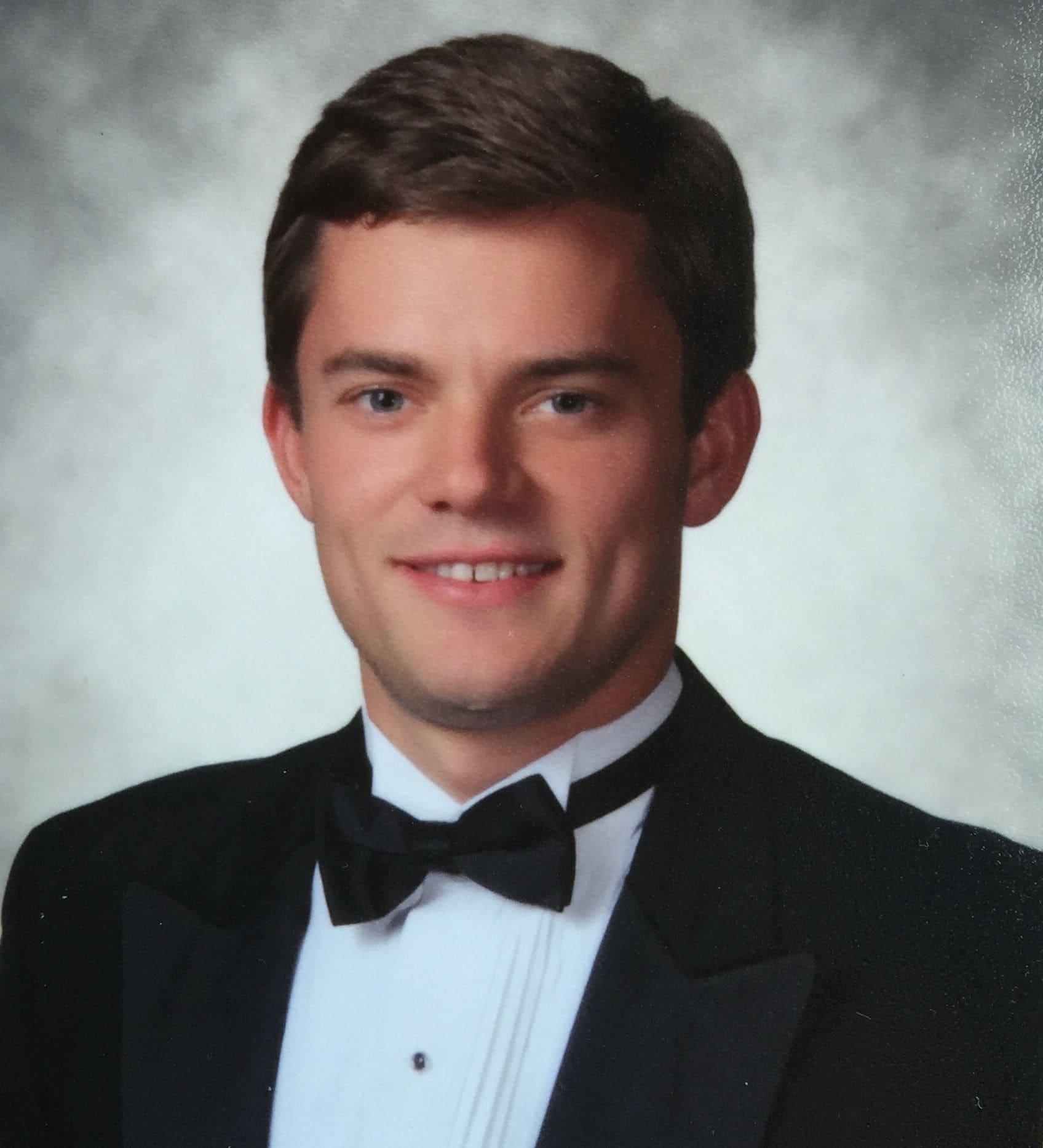 Man in tuxedo smiling for portrait photo.
