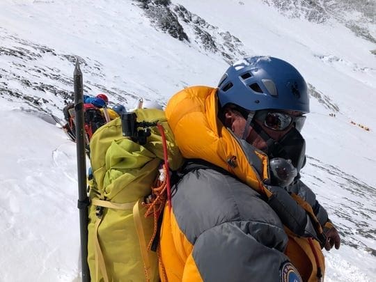 Climber in bright gear ascending snowy mountain.