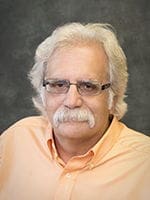 Man with glasses and mustache, wearing orange shirt.