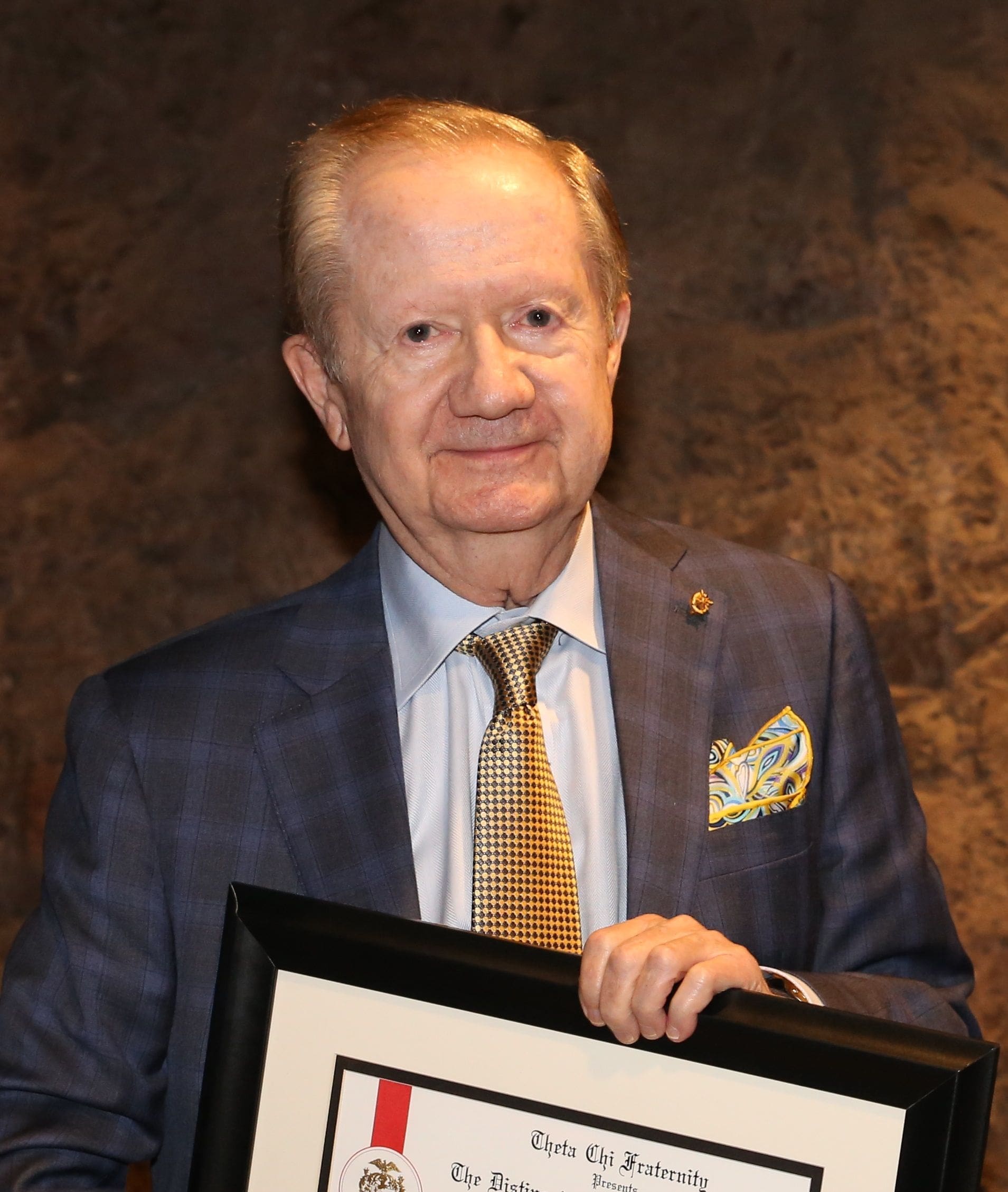 Man in suit holding a framed artwork.