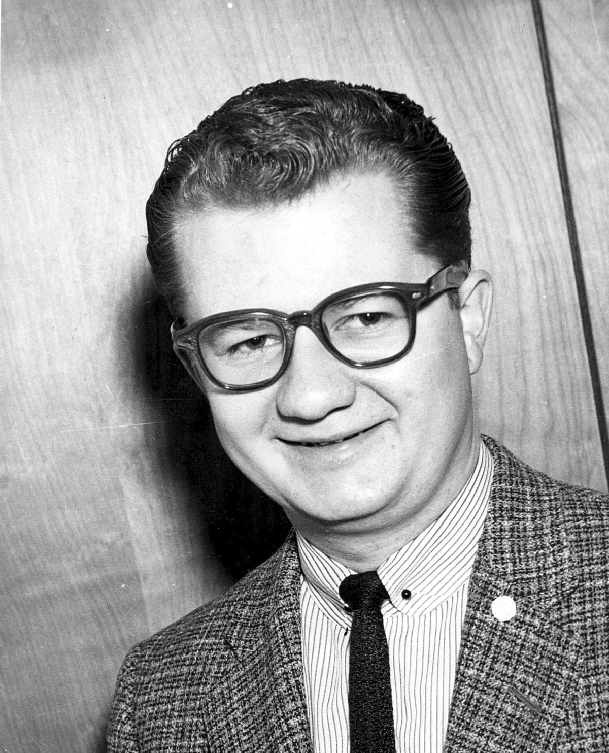Smiling man in glasses with a patterned blazer.
