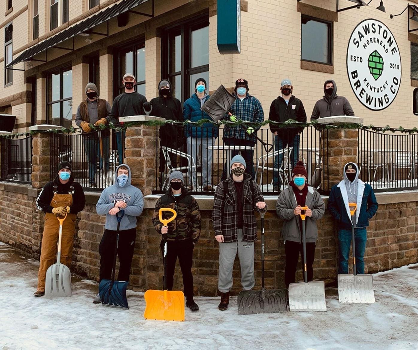Group of people with shovels outside brewery.