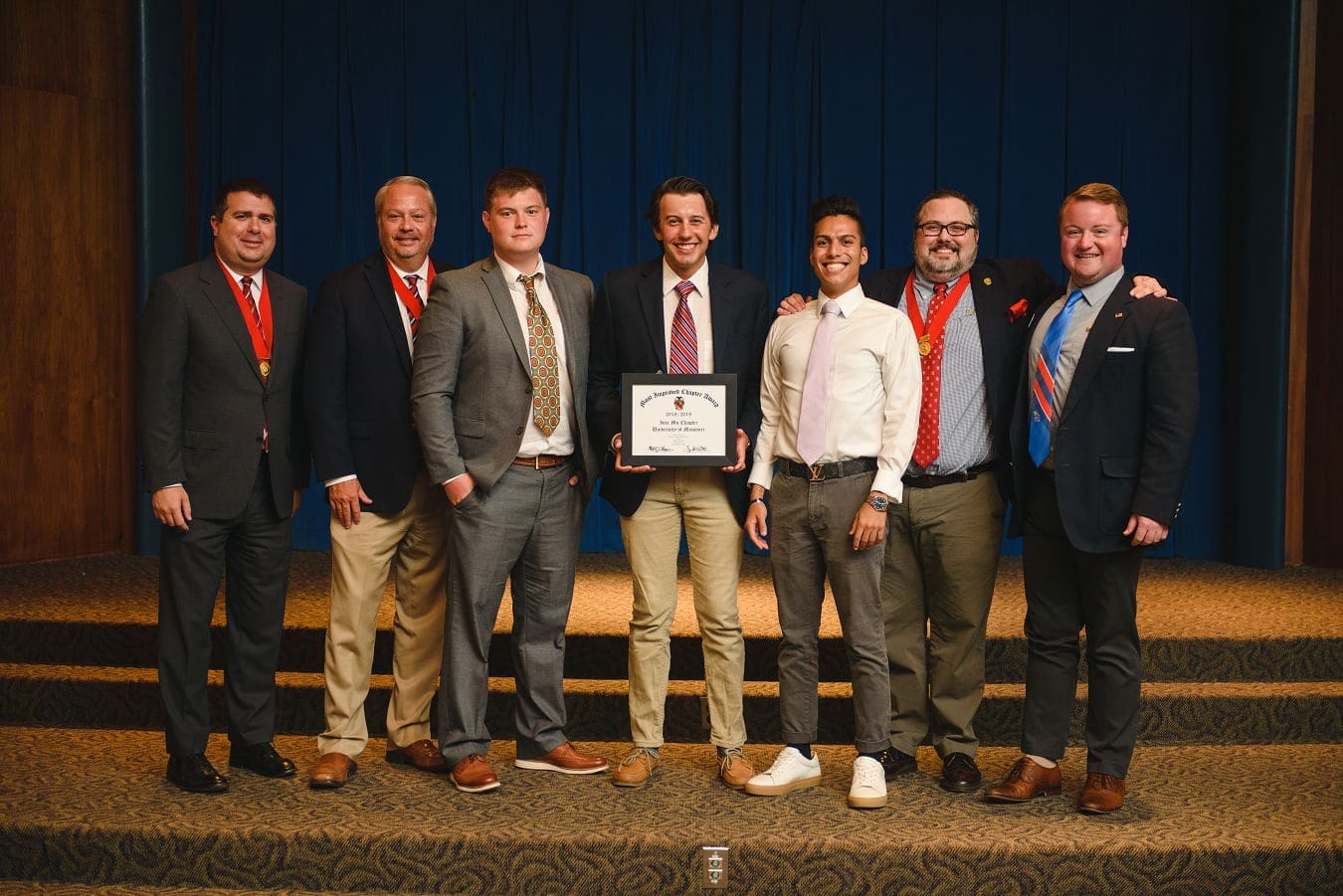 Group of men celebrating an award presentation.