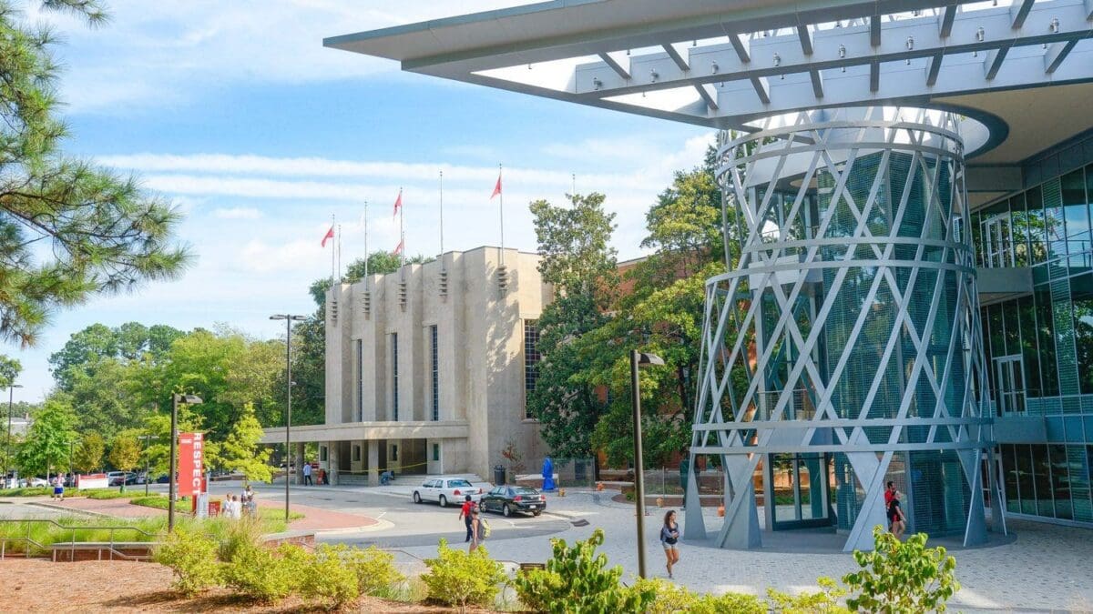 Modern building with flags and greenery outside.
