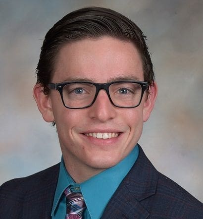Young professional man in formal attire smiling.