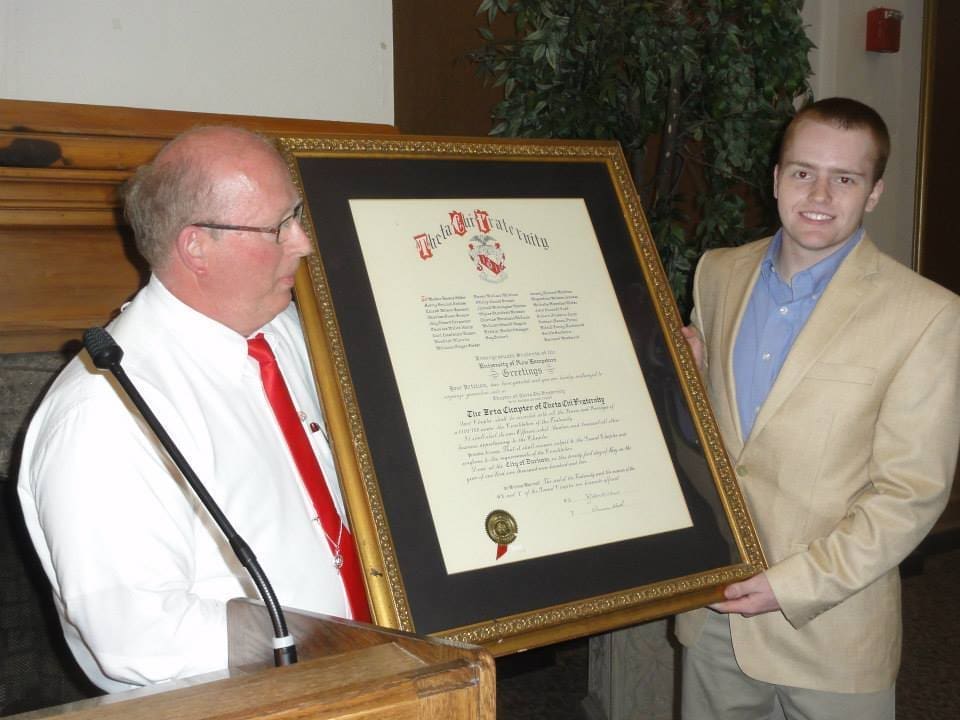 Men presenting a framed award certificate at event.