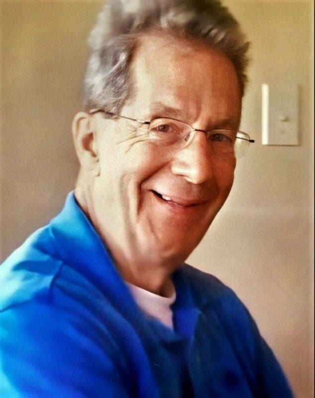 Smiling older man in blue shirt indoors.