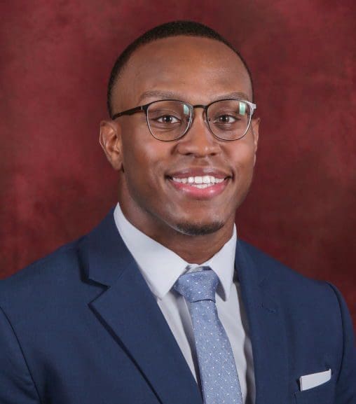 Smiling man in a blue suit and glasses.