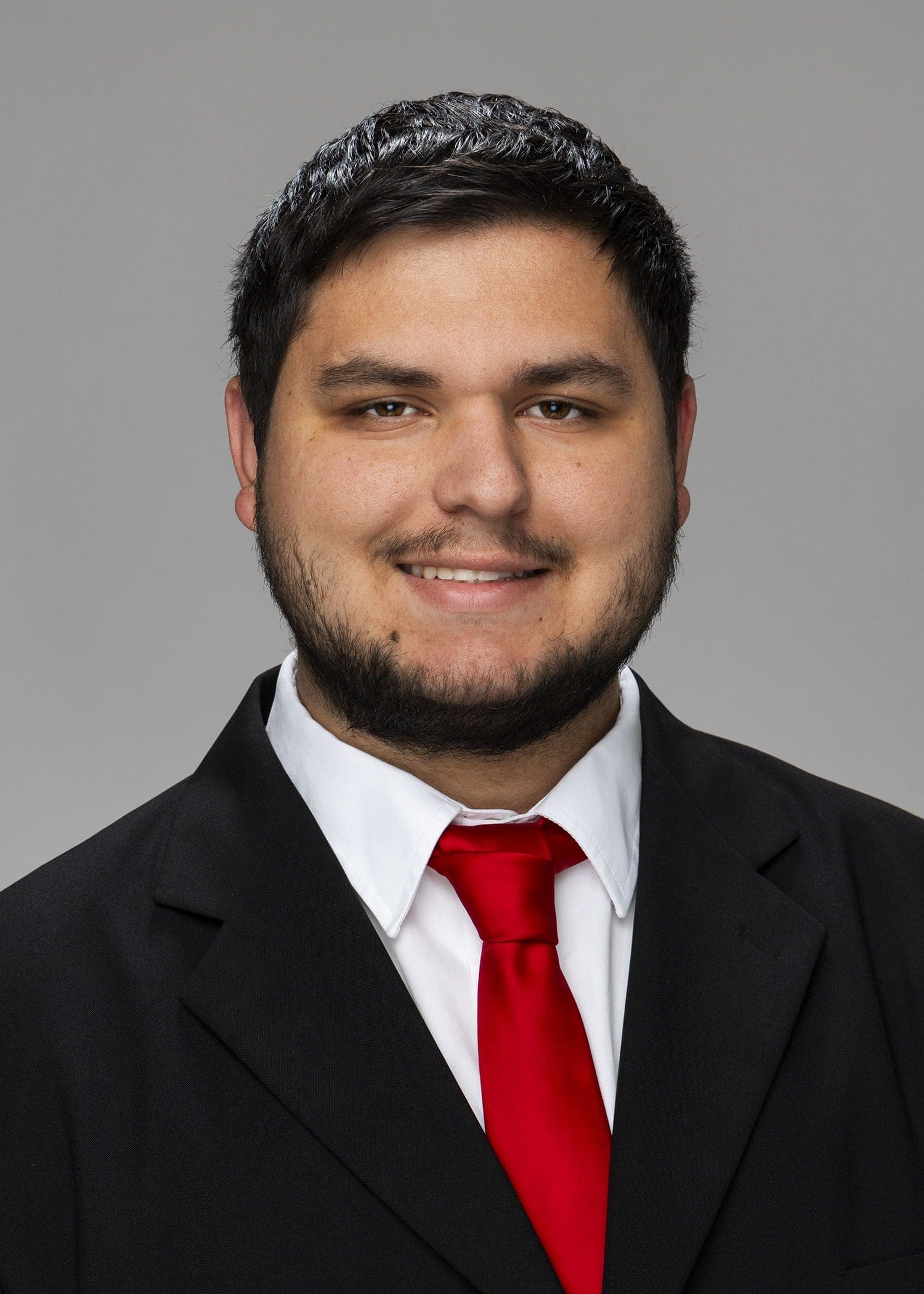 Smiling man in suit with red tie.