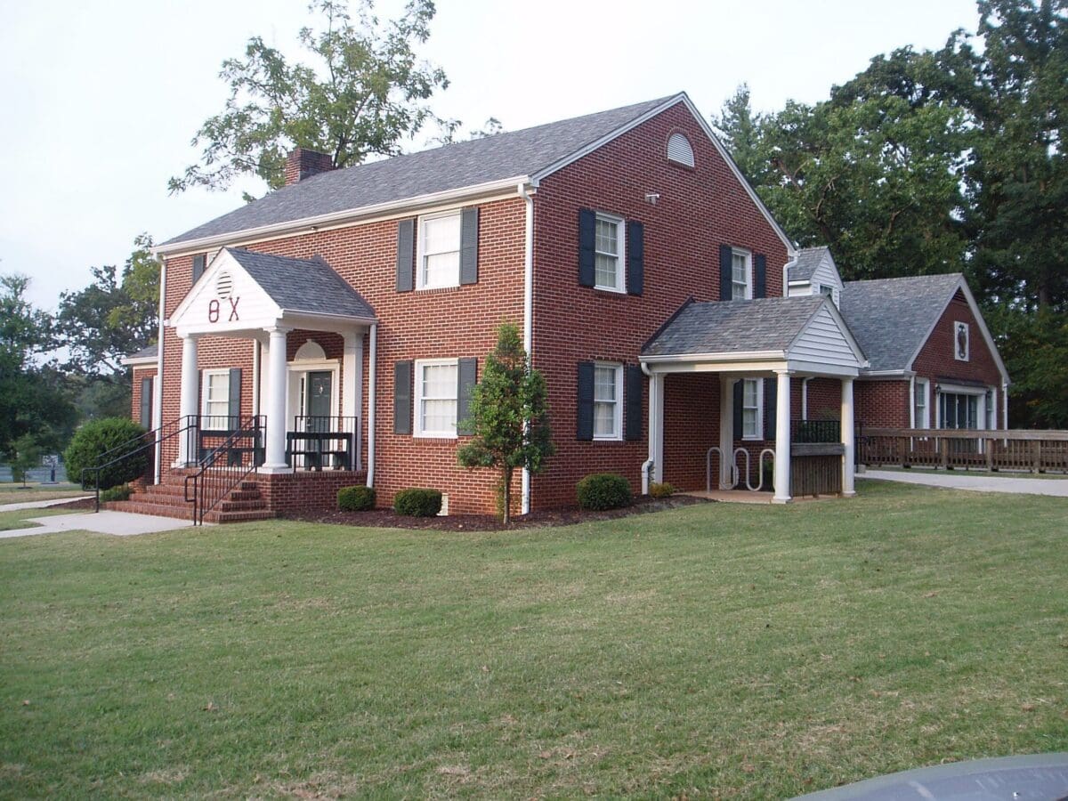 Brick house with green lawn and porch.