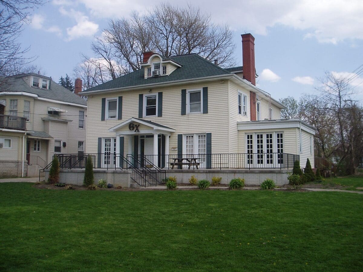 Two-story house with green roof and porch.