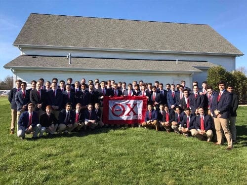 Group photo of fraternity members with banner.